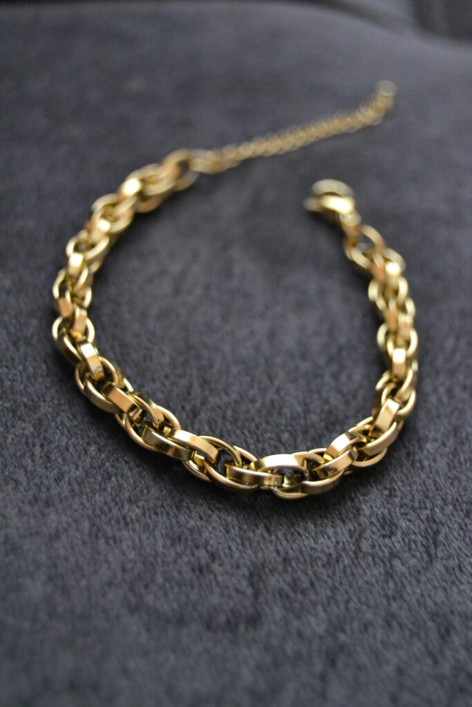 Close-up of a luxurious gold chain necklace displayed on a dark velvet background, emphasizing elegance and style.