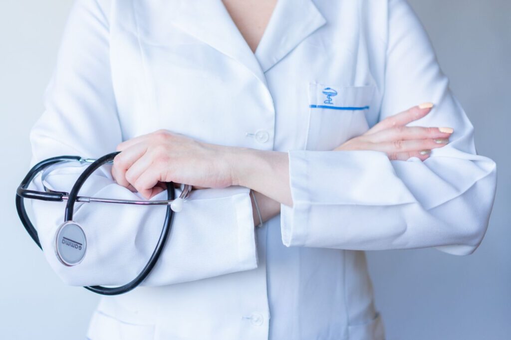 A close-up image of a doctor in a white coat with a stethoscope and arms crossed.