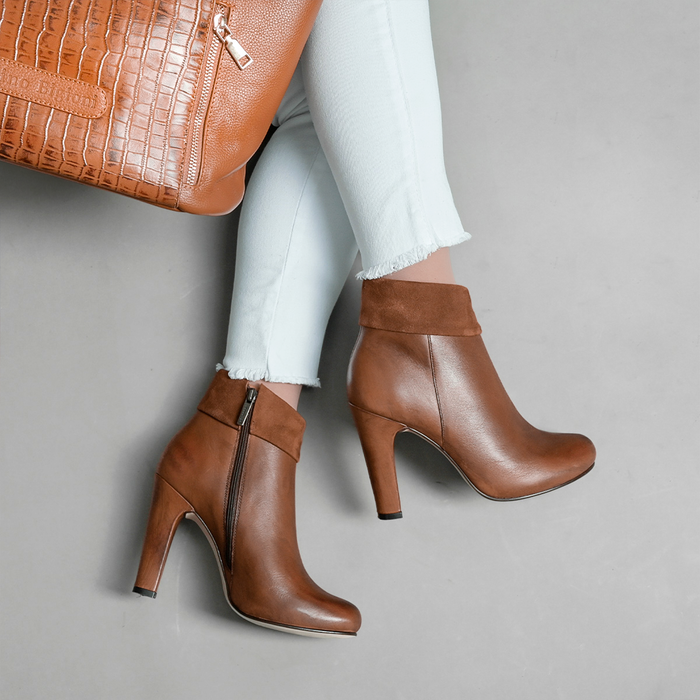 Elegant brown leather boots paired with a chic handbag, perfect for a fashionable outfit.