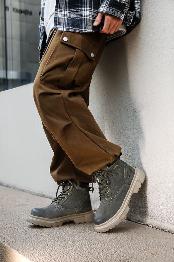 Close-up of casual urban outfit featuring brown pants and grey boots.